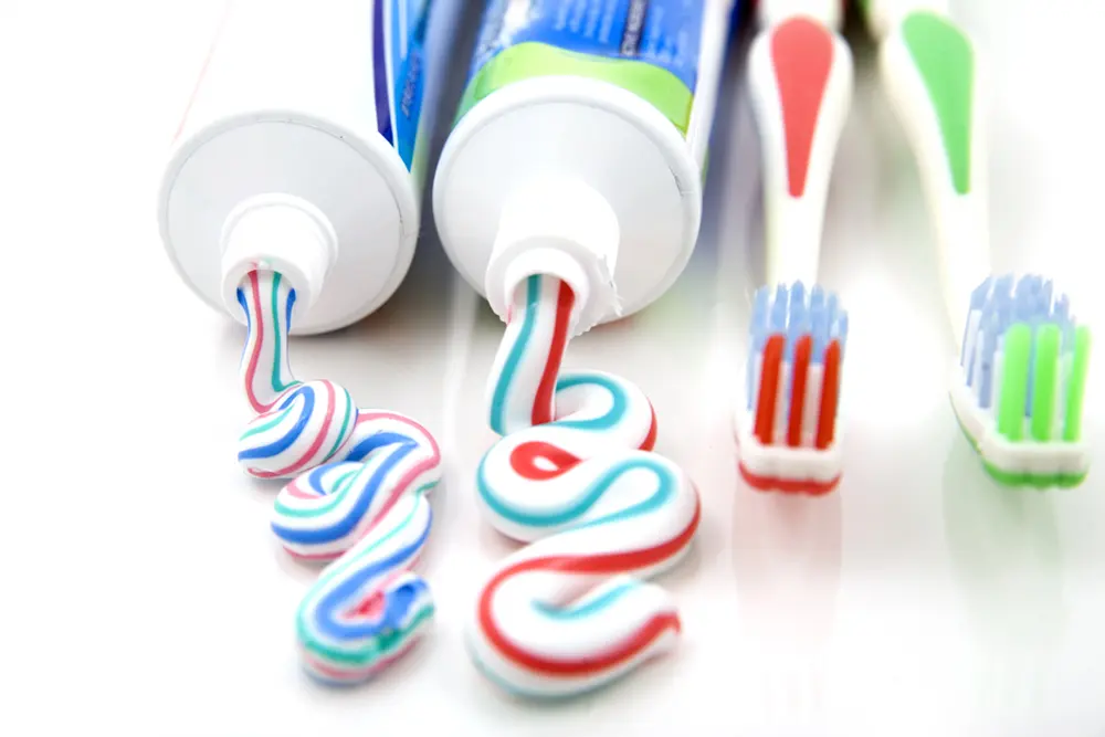 Spry Products | VP Dental | Spry Dental Products in Raleigh Two tubes of multicolored toothpaste squeezed onto a surface, with three toothbrushes