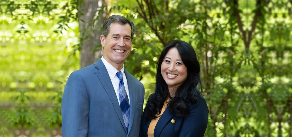Dr. Nordone and Dr. Oh standing outdoors in front of greenery, both smiling at the camera