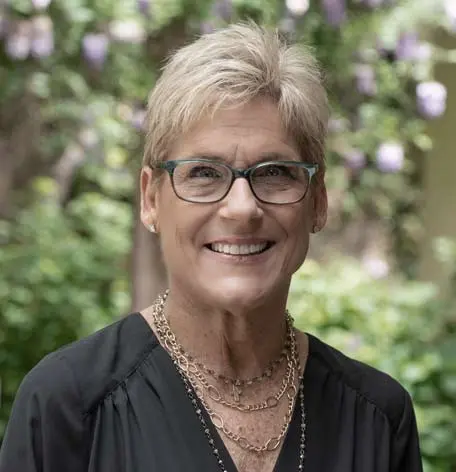Head shot of Maddi, Scheduling Coordinator, smiling confidently in a black top and glasses