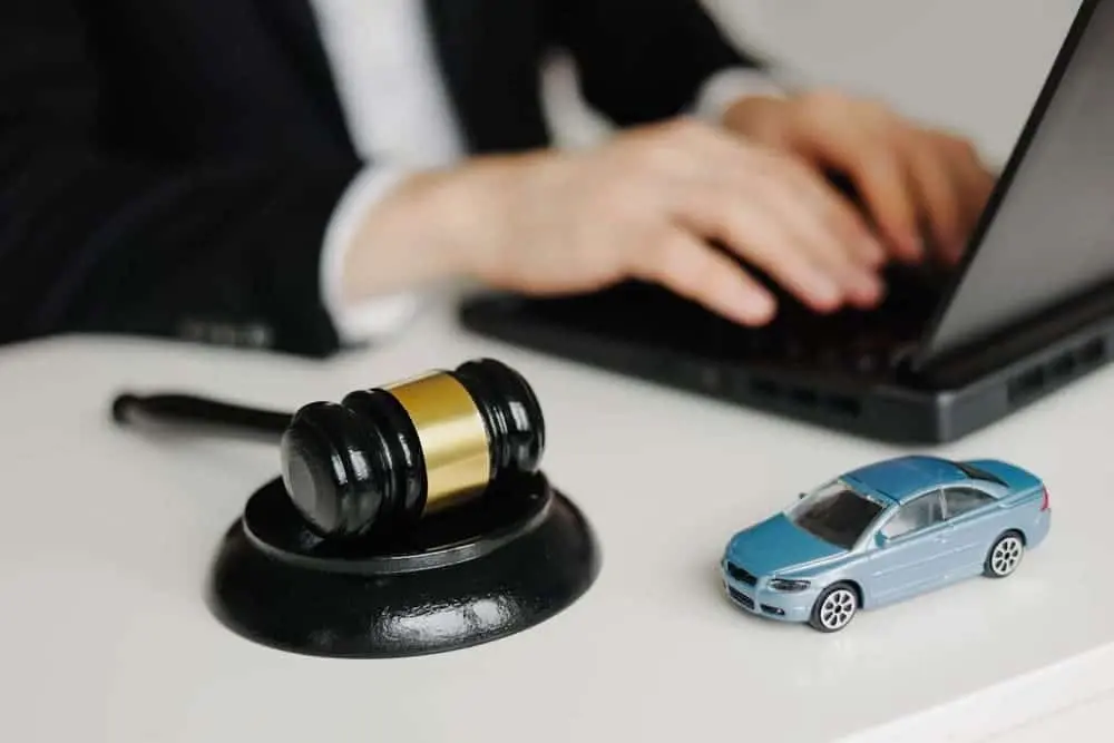 Una persona de traje teclea en un ordenador portátil con un mazo y un coche de juguete sobre el escritorio, símbolo del asesoramiento jurídico para reclamaciones por accidentes de tráfico en Nueva York.