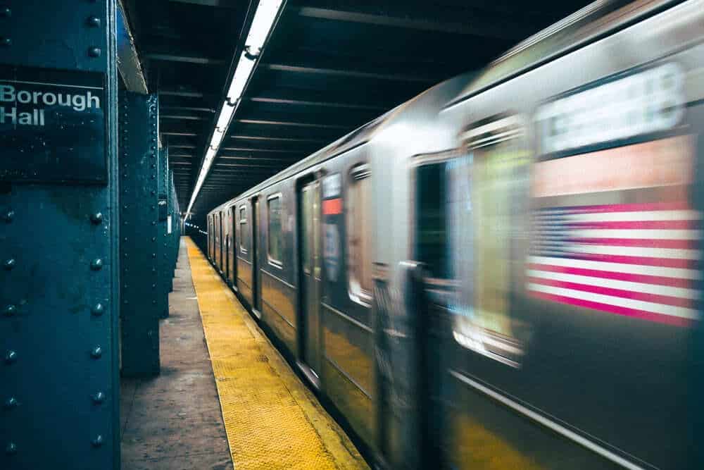 A blurred subway train speeding through the Borough Hall station in New York, highlighting the risks of train accidents that a New York train accident lawyer can address.