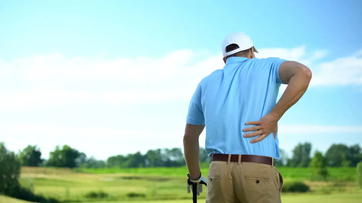 Jugador de golf que siente un fuerte dolor lumbar tras golpear la bola, traumatismo