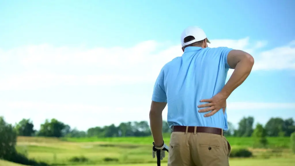 Jugador de golf que siente un fuerte dolor lumbar tras golpear la bola, traumatismo