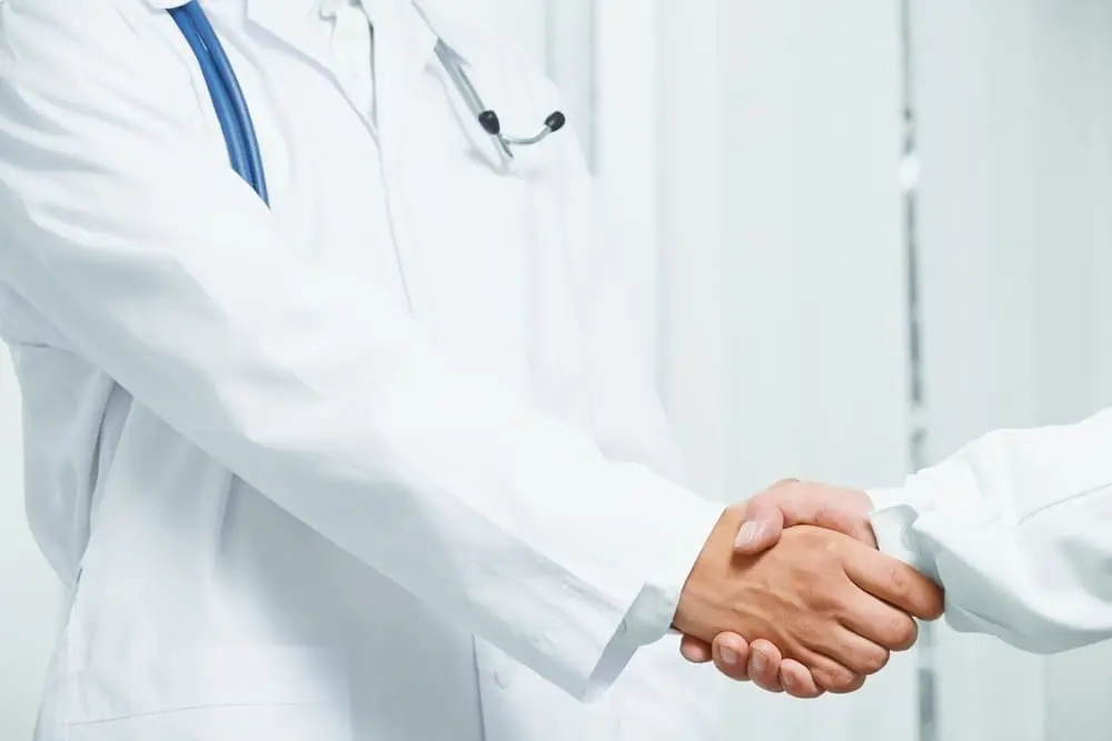 Especialista en columna vertebral en Nueva York dando la mano a un paciente, representando afiliaciones hospitalarias de confianza y atención experta en columna vertebral.