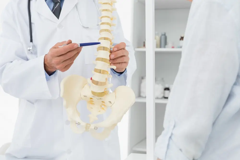 Spine specialist pointing at a spinal model with a pen to explain structural or nerve issues.
