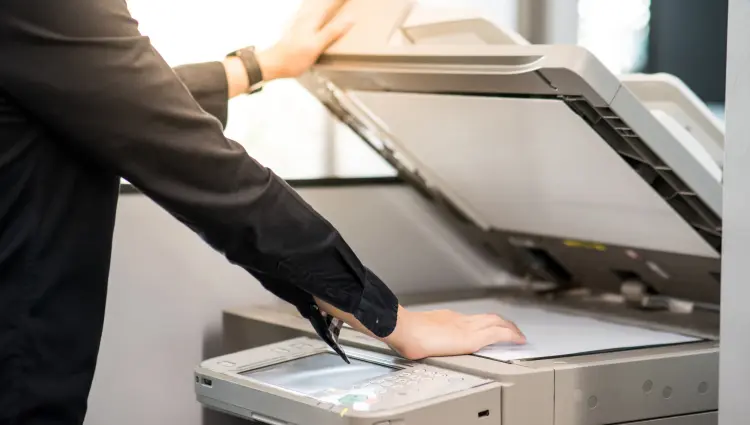 Office Worker Scanning Document on Multifunction Printer Office employee opening scanner lid on a multifunction printer to scan a document
