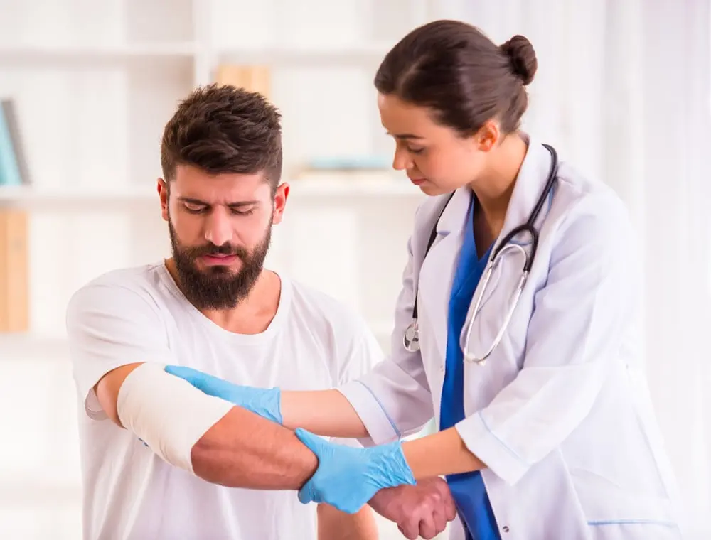Un médico examina la lesión en el brazo de un paciente en una consulta médica.