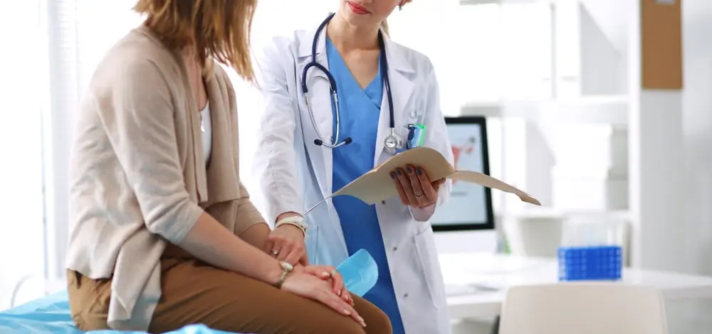 Médico revisando historiales médicos con un paciente en una consulta.