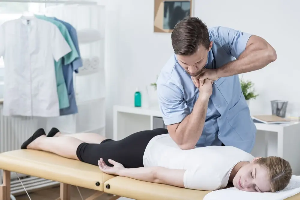 Male practitioner providing hands-on back therapy to a woman in a clinic as part of chiropractic-style spinal care for back pain relief in Queens NY