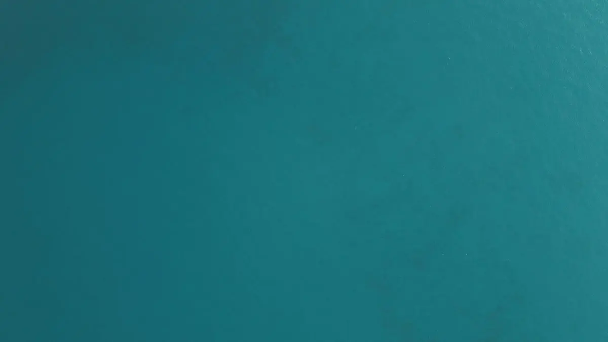 A close-up view of a textured teal surface displaying subtle variations in color and sheen, creating a visually interesting backdrop suitable for various design applications