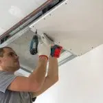 Construction worker assemble a suspended ceiling with drywall