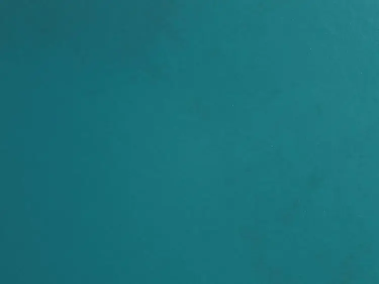 A close-up view of a textured teal surface displaying subtle variations in color and sheen, creating a visually interesting backdrop suitable for various design applications