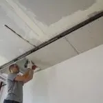 Construction worker assemble a suspended ceiling with drywall