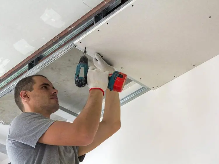 Construction worker assemble a suspended ceiling with drywall