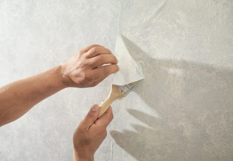 Worker applying wallpaper to wall at home.