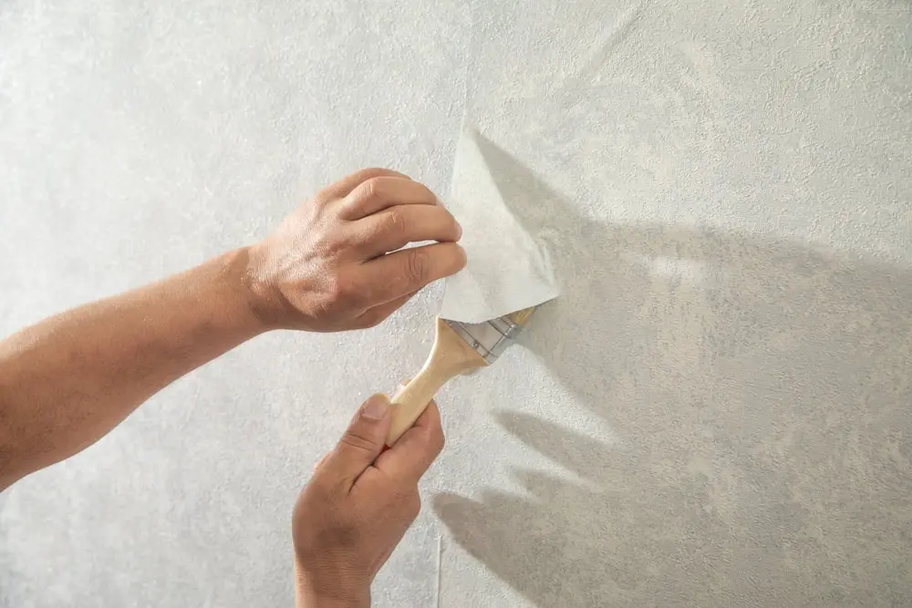 Worker applying wallpaper to wall at home.