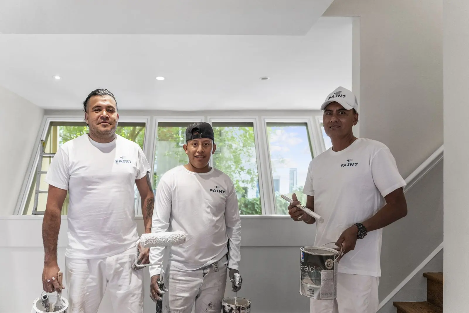 Three PAINT Philadelphia painters with rollers and paint buckets inside a finished home