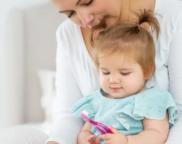 Mother holding baby while she plays with toy