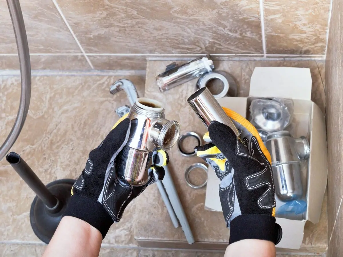 Sanitary technician repairs plumbing trap from sink in bathroom