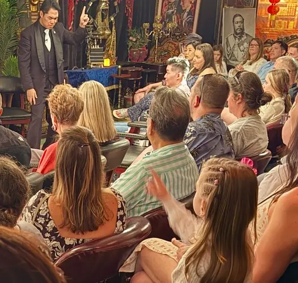 Magician performing for a captivated audience in an intimate setting, with guests eagerly watching the show.