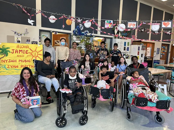 Group photo of children and caregivers at a community event, with some in wheelchairs.