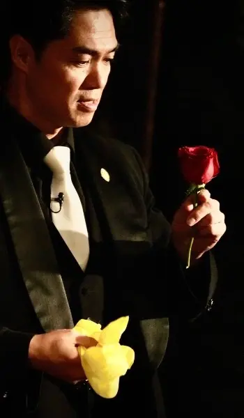 Magician revealing a rose from a cloth during a magical performance, with a focused expression.