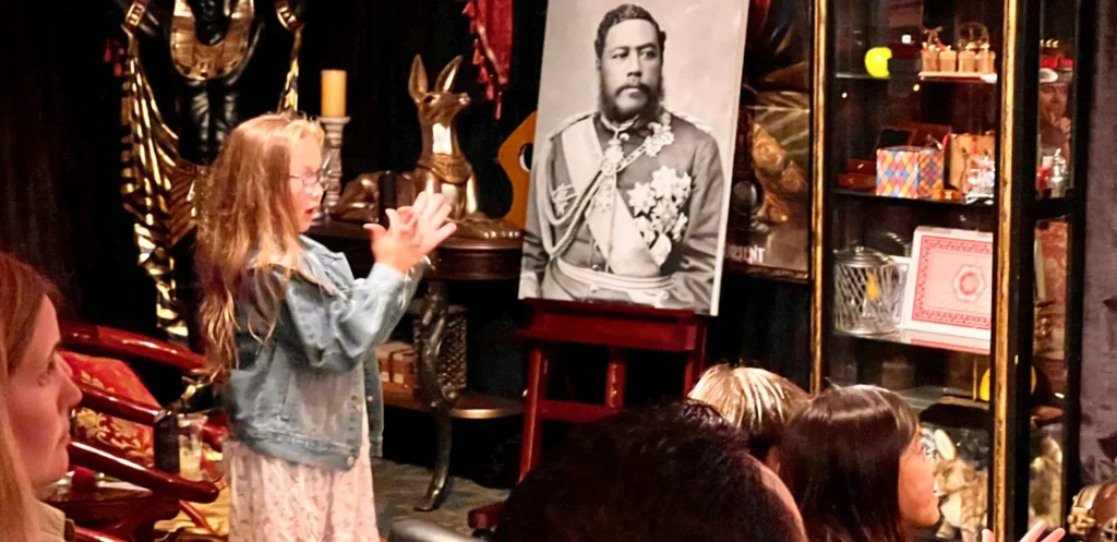Young girl interacting with a magician, performing magic in front of an audience.