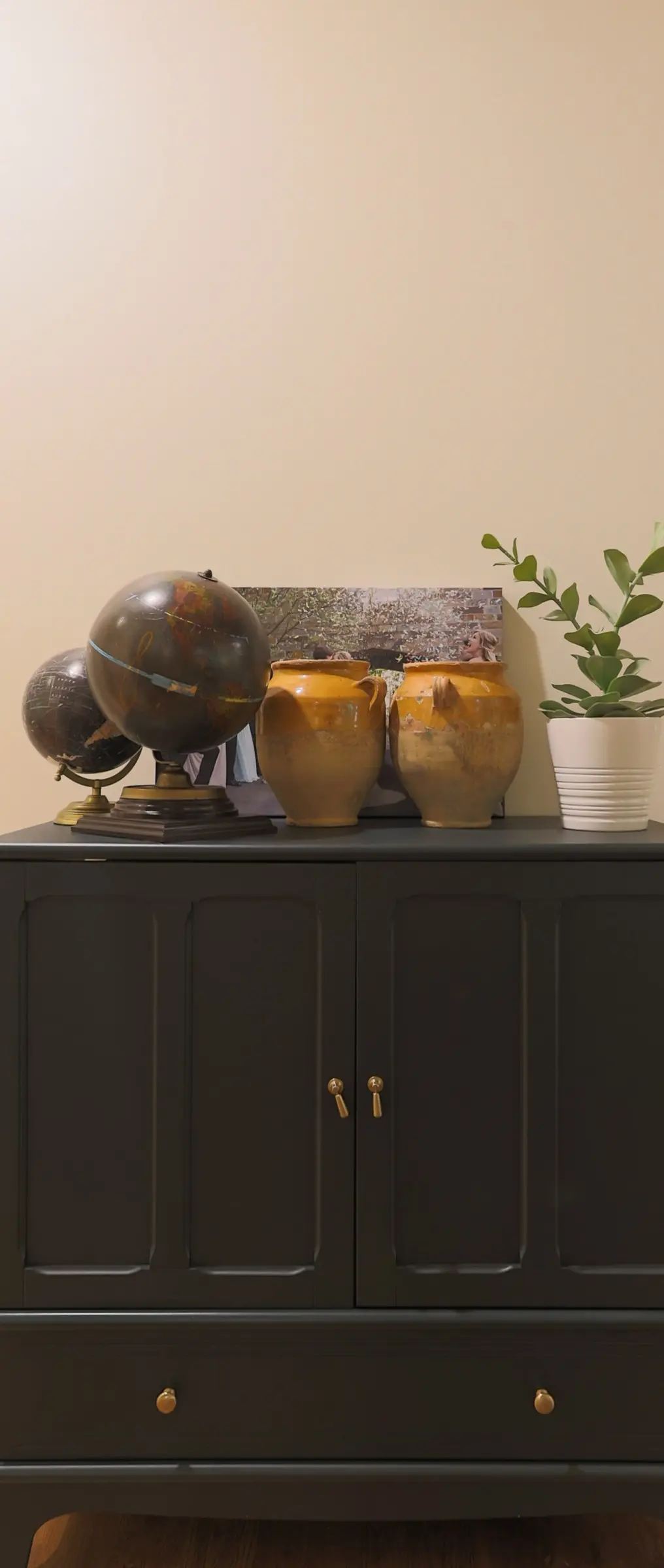 Charcoal painted cabinet against a soft cream wall.