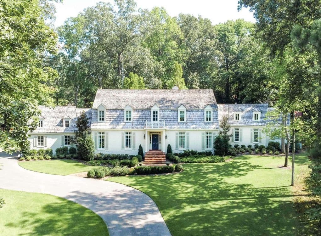 White painted brick traditional home with a curved drive and wide green lawn
