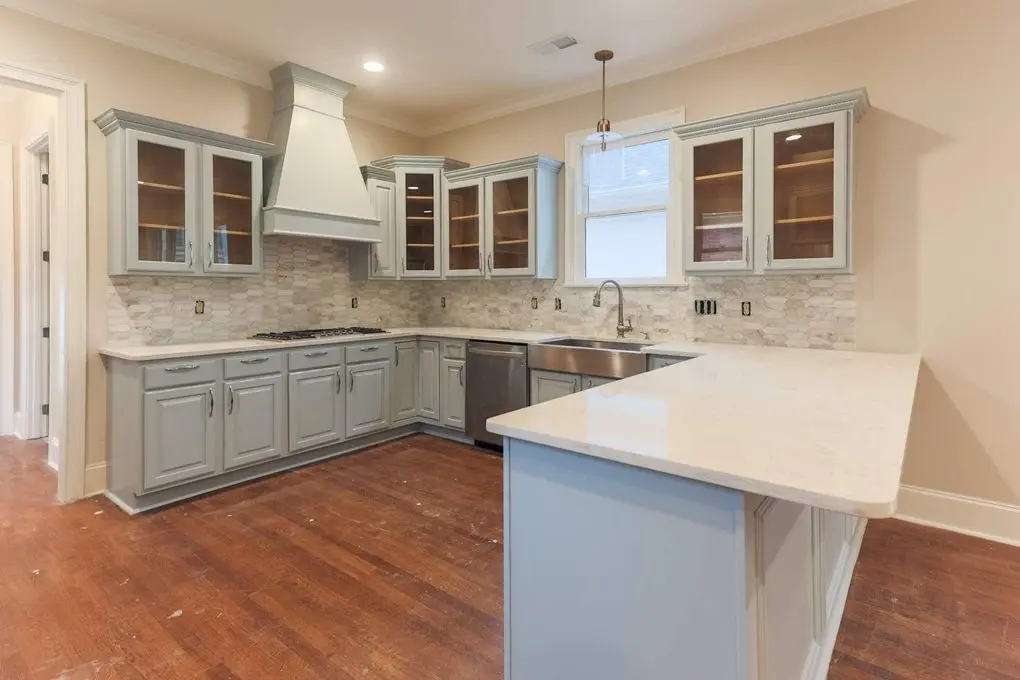 Kitchen with gray blue lower cabinets, white upper cabinets and white counters