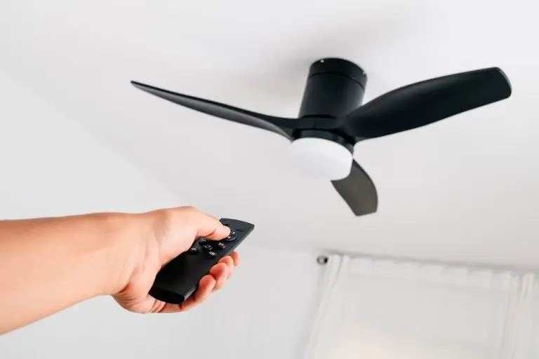 man operating a ceiling fan with remote control