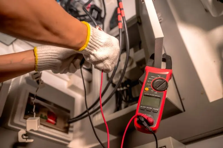 Close up unrecognized electrician in safety gloves upgrading home electric system for EV charging point