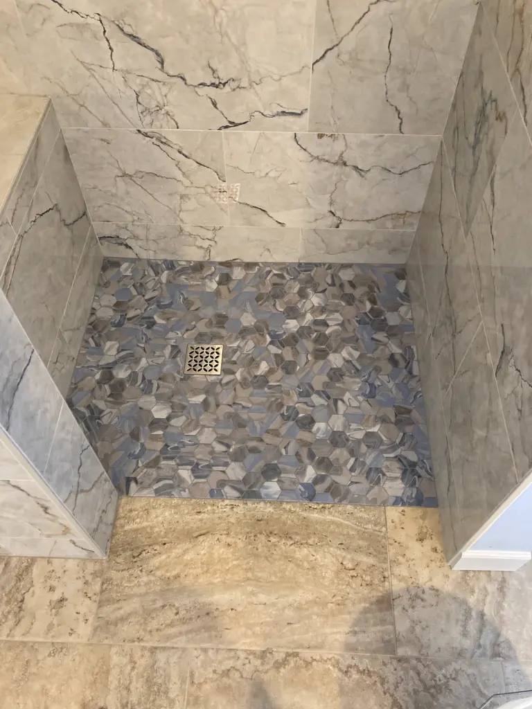 Blue-gray hexagonal shower mosaic, square drain and stone-look wall tile