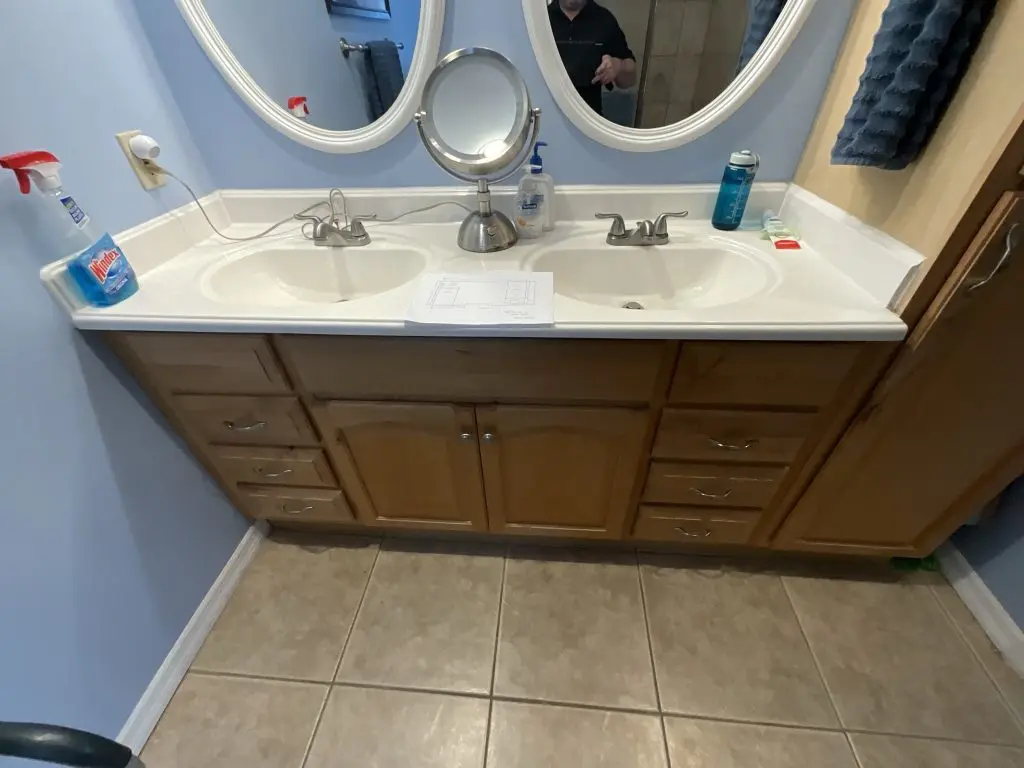 Original wood vanity, white double-sink countertop and oval mirrors before the Venice bathroom remodel