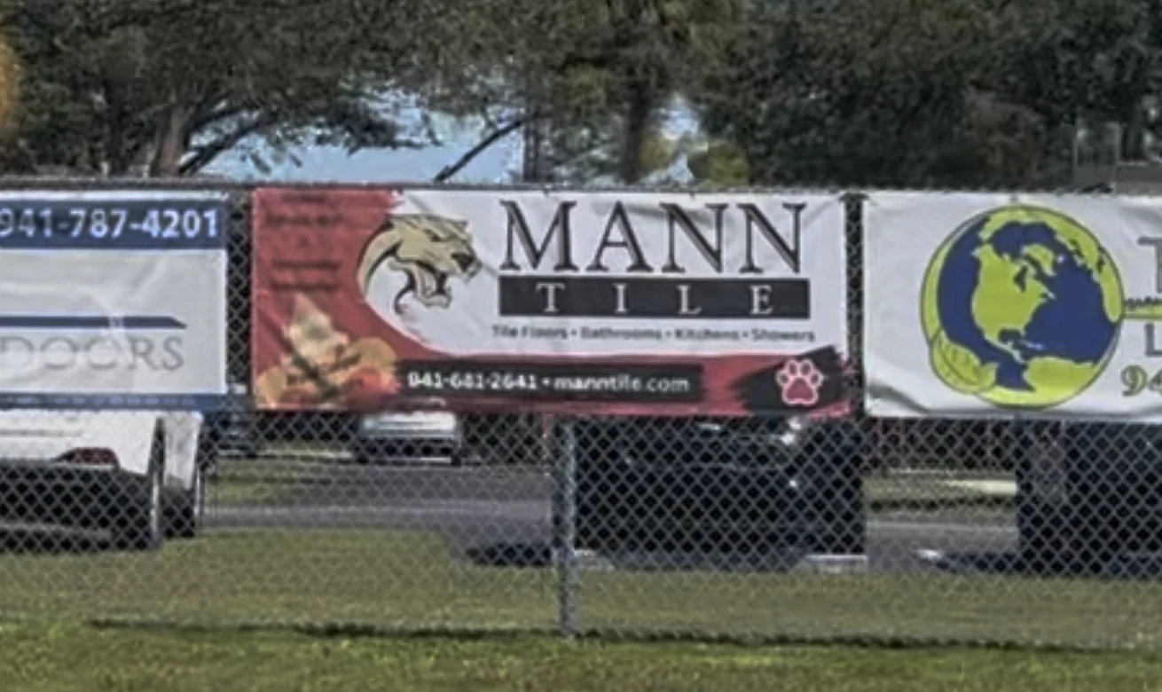Mann Tile sponsorship banner on the fence at L.A. Ainger Middle School