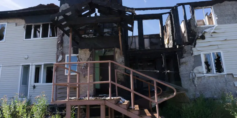Edificio residencial quemado con estructura carbonizada, ventanas dañadas y una escalera, que ilustra los daños causados por incendios relevantes para las reclamaciones de seguros.