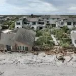 Zona residencial amenazada por el huracán con hogares destruidos y escombros, lo que ilustra la necesidad de ajustar los seguros de desastres en Texas.