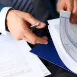 Manos revisando documentos de seguros y gráficos, destacando la asistencia de reclamaciones y servicios de evaluación por los Ajustadores Públicos de Santex en Texas.