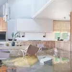 Cocina inundada con daño al agua, mostrando muebles y electrodomésticos sumergidos, destacando el impacto de las reclamaciones del seguro de daños al agua.