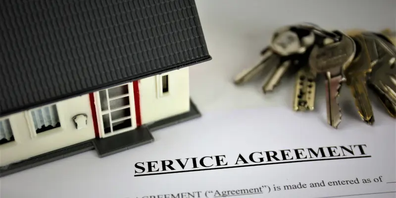 Model house and keys on a service agreement document, symbolizing home insurance claims and negotiation services by Santex Public Adjusters.