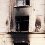 El exterior quemado de un edificio con paredes ennegrecidas y una ventana dañada, que ilustra las necesidades de restauración de daños causados por incendios en Houston, Texas.