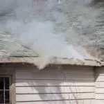 El humo se hunde desde el techo de un edificio, lo que ilustra los efectos del daño causado por incendios relevantes para las reclamaciones de seguro.