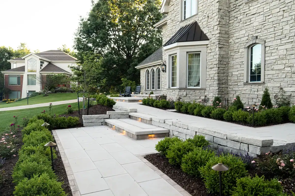 Trusted Landscaping Company Serving Madison, WI 14 Bluestone walkway and steps leading to a stone home, framed by landscape beds and path lighting.
