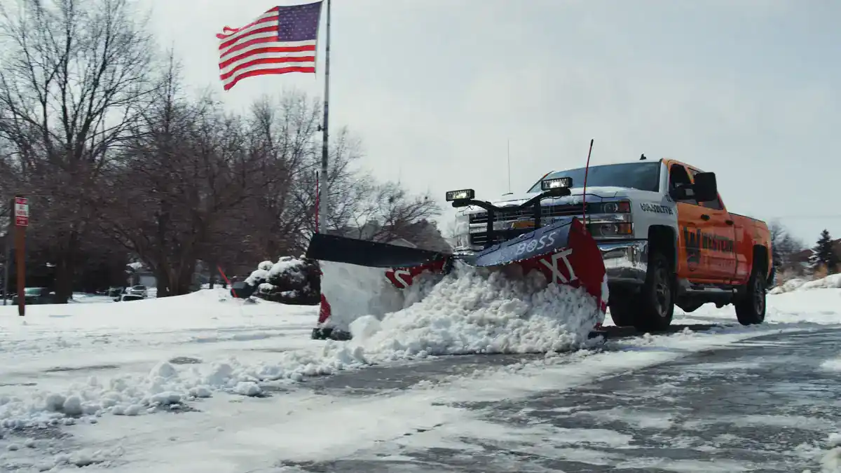 Western Landscape truck with a plow clearing snow from a driveway