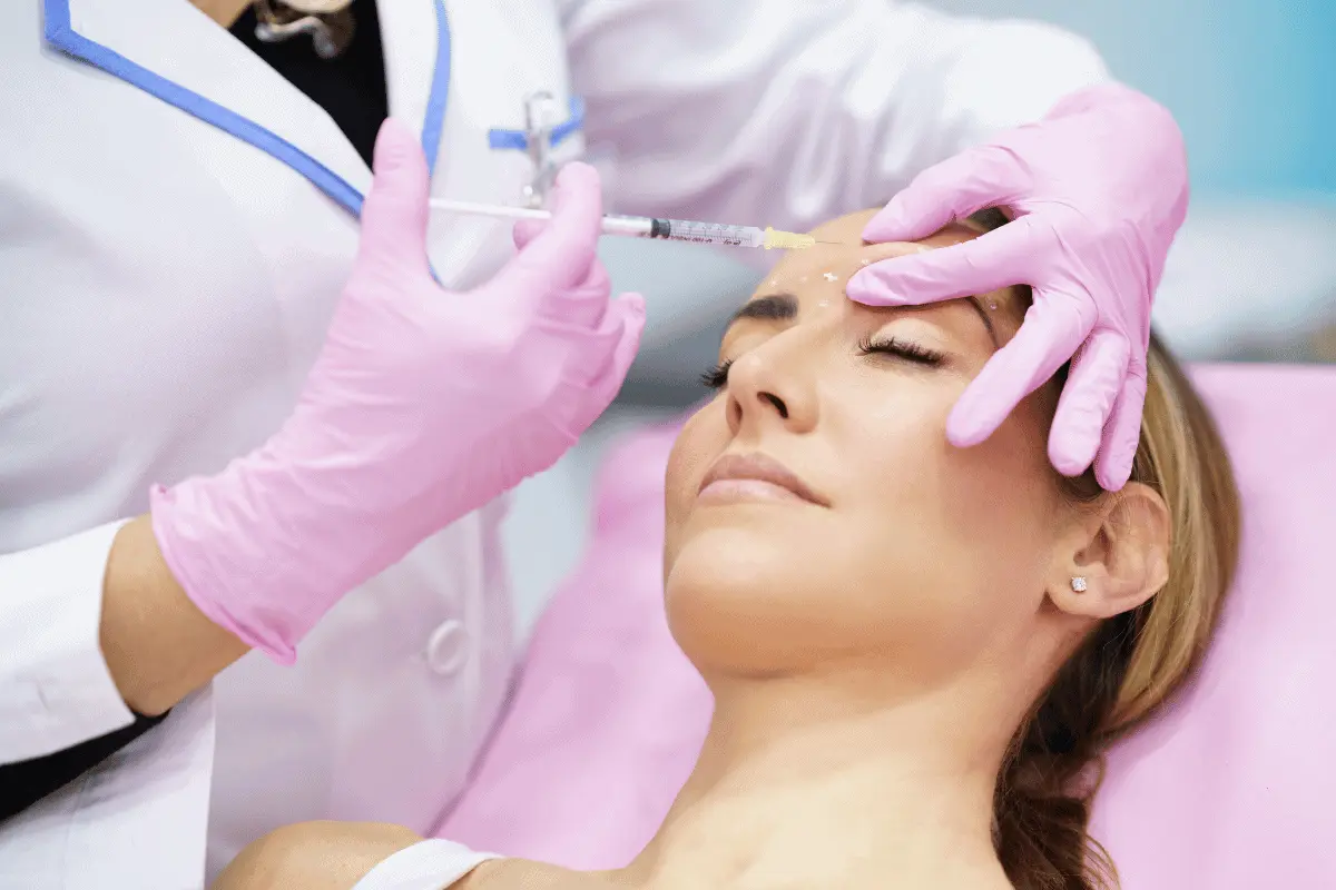 Woman with eye closed while medical professional injects botox